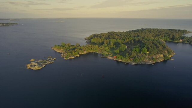 Aerial view of a small island with a serene pier and lush forest along the coastline, Karlshamn Citadel, Sweden.