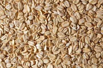 Uncooked Oat Flakes background - Top View, Flat Lay. Scattered Dry and Raw Oat Flakes. Healthy Breakfast and Diet Eating Ingredients