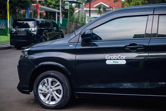 Jakarta, Indonesia - October 16, 2024: An online taxi car from GrabCar parked on the street. A word GrabCar plus is stuck on the car door.