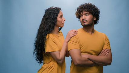 Offended Arabian man Indian husband boyfriend ignoring Latino Hispanic woman wife girlfriend asking forgiveness apologizing after quarrel conflict guilty saying sorry apology at studio blue background