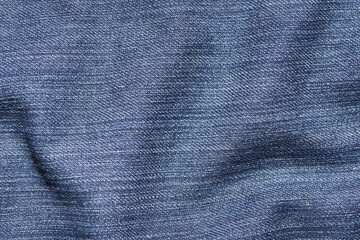 Close-up of blue denim fabric with subtle textured pattern creating a soft and wavy look perfect for fashion, sewing, and textile design concepts.