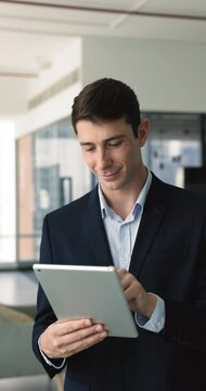 Young businessman, office employee holds digital tablet device for business communication, managing tasks, review sales stats, do analytics using application. Modern tech usage, workflow, remote chat