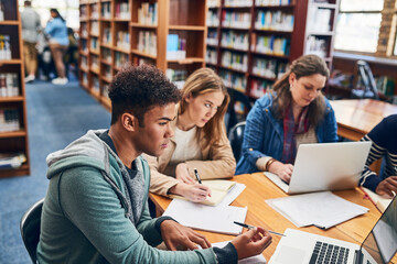 Students, group and learning with reading, laptop and development in campus library at university. People, men and women with books, review and thinking by computer with planning for exam at college