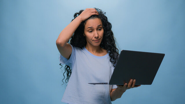 Shocked frustrated Indian student girl Latino upset woman businesswoman with computer failure stressed shock with laptop bad news business online problem failed exam results at studio blue background