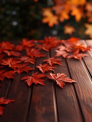 Obraz premium Red maple leaves scattered on a rustic wooden table, a classic autumnal scene with a warm and inviting feel. The blurred background of fall foliage adds a touch of depth and color.