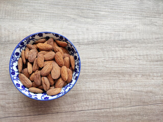 Natural fresh almonds in a decorative plate on a wooden background