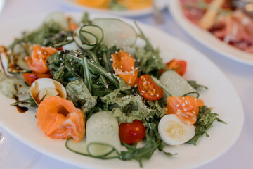 salad on a plate in a restaurant with salmon arugula and cherry tomatoes