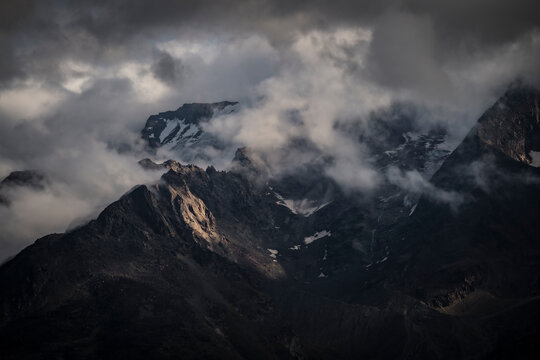 View of majestic snow-capped peaks and dramatic clouds in saas valley, valais, switzerland.