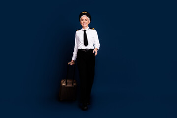Full length photo of lovely pensioner lady commercial pilot suitcase walk dressed aviator uniform isolated on dark blue color background