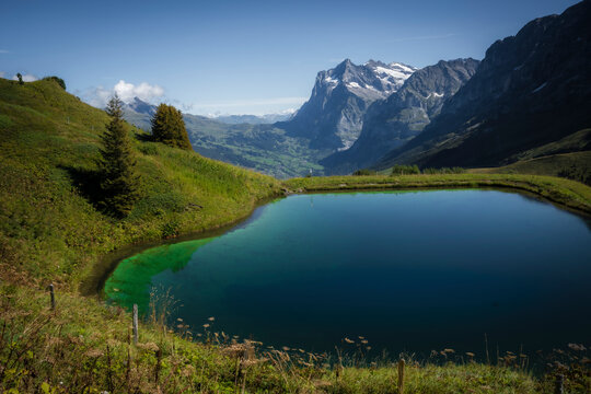View of serene lake surrounded by majestic mountains and picturesque valley, Wengen, Switzerland.