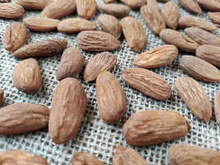 Natural brown fresh almonds on woven jute fabric