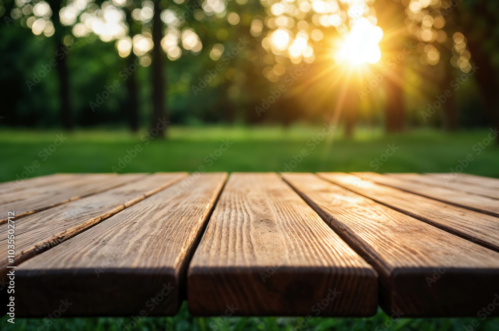 Poster empty wooden table illuminating by setting sun in the park with green grass and trees blurred backgr