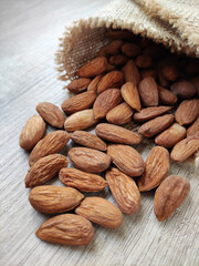 Natural brown fresh almonds on woven jute fabric