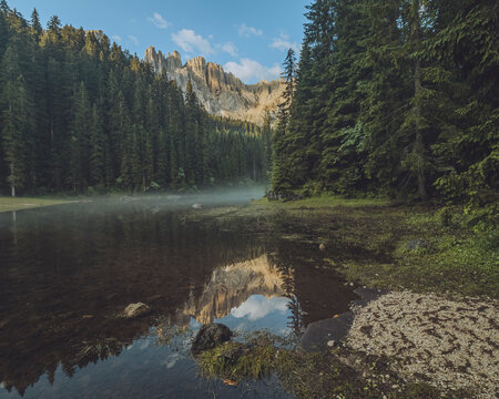 View of Lago di Mezzo surrounded by tranquil forests and majestic mountains, Nova Levante, Italy.