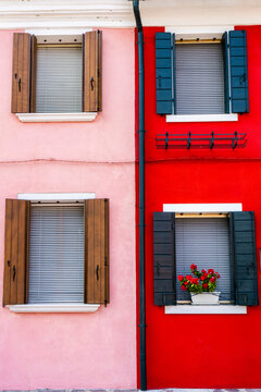 View of colorful houses with vibrant windows and flower boxes, Burano island, Italy.