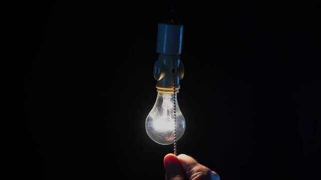 A man turning on a classic pull chain light