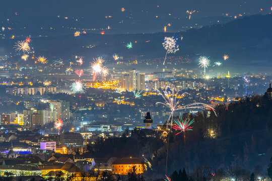 View of vibrant fireworks illuminating the skyline over the city of Graz with the iconic clocktower, Styria, Austria.
