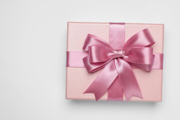 Gift box with pink bow on light grey background, top view