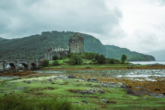 View of eilean donan castle surrounded by lush greenery and water, loch duich, scottish highlands, united kingdom.