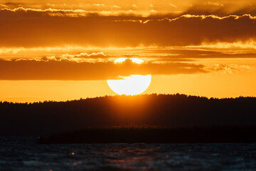 Epic sunset sky with big bright sun going behind the horizon in Lithuania.
