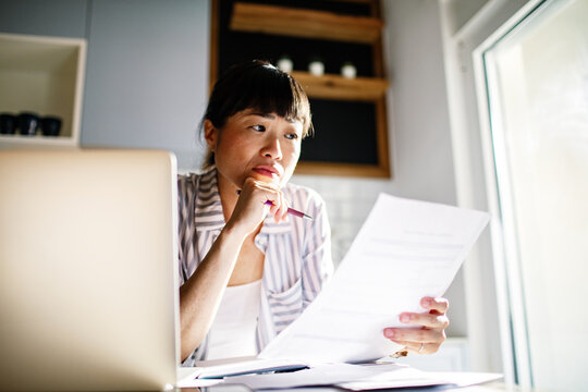 Asian woman reviewing documents while working from home