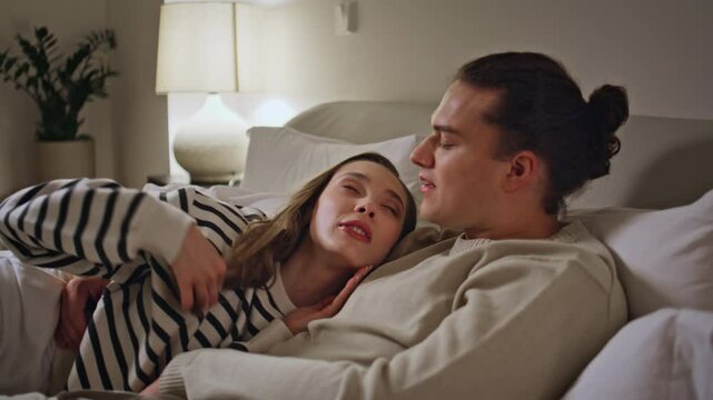 Happy sweethearts lying bed at cozy domestic evening closeup. Beautiful woman