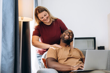 Fototapeta premium Happy African American man enjoying massage of his shoulders making by girlfriend