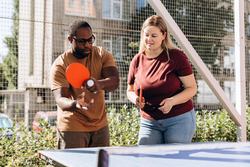 Happy people playing table tennis outdoors, having fun
