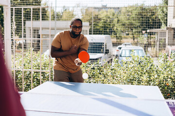 Young African American man playing table tennis outdoors