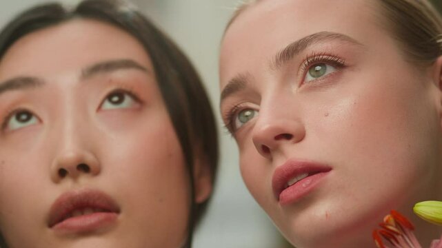 Two sensual elegance beautiful multiethnic girl diversity models natural beauty skin cosmetology dermatology bloom multiracial Japanese Asian Chinese Caucasian females women holding flowers near faces