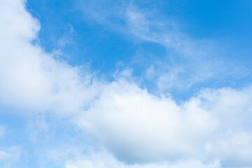 Fluffy white clouds drift across a clear blue sky, painting a breathtaking summer cloudscape