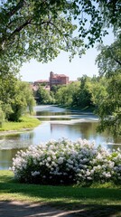 Fototapeta premium Lilac bushes flourish by the river in St. Jur, with a grand building rising in the background under the bright spring sun.