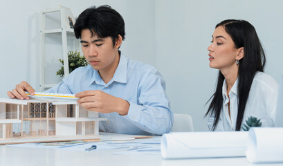 Fototapeta premium Portrait of cooperative engineer team working together to measure house model by using ruler and architectural equipment. Creative business design and teamwork concept. Immaculate..