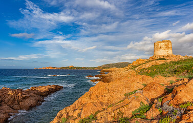 Red porphyry rocks and the historic tower of Isola Rossa at golden hour, municipality of Trinità...