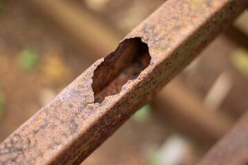 Close up detail of a very rusty old iron with a large hole in the middle.