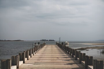 Obraz premium A long wooden pier extending into a body of water under an overcast sky