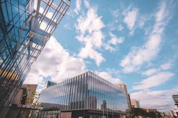 Fototapeta premium A modern high-rise building with a grid-like facade against a blue sky with white clouds