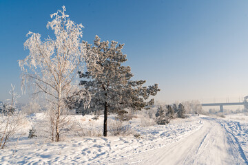 Winter landscape scenery with country road through the snow-covered fields, rural area.