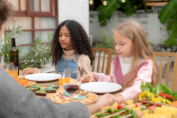 Grandfather, parents, and the teenage girls are all having dinner together at home