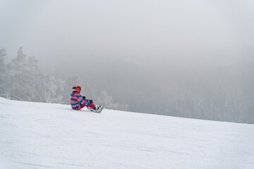 Snowboarder sits high in the mountains on the edge of the slope. Winter vacation concept