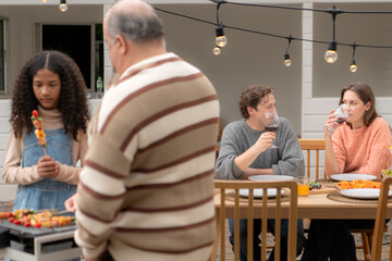 Grandfather, parents, and the teenage girls are all having dinner together at home