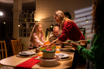 Grandfather, parents, and the teenage girls are all having dinner together at home on Christmas night