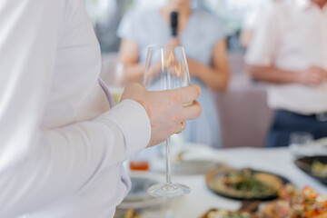 a man holds a glass of champagne in his hand at a celebration in a restaurant