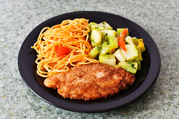 Almuerzo de pechuga de pollo empanizada acompañado de fideos con salsa de tomate y ensalada de pepino.