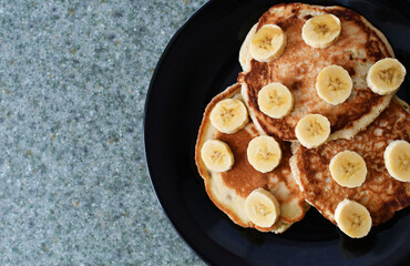 Desayuno de panqueques con banano y una taza de café, toma superior. Espacio para texto al lado izquierdo.