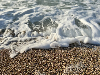Bubbling foam rolling over pebbles