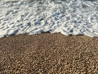 Foam washing over pebble beach