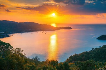 Fototapeta premium Golden sunlight gently setting over the horizon, illuminating the Andaman Sea, with a panoramic view of Windmill View Point, Phuket.