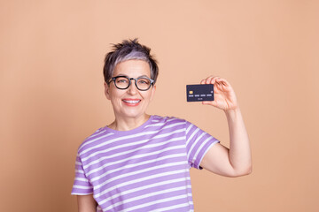 Photo of lovely nice woman wear striped stylish clothes hand hold bank card isolated on beige color background