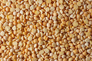 Uncooked Polished Split Peas Background. A Culinary Canvas of Dry Yellow Peas, Creating a Lively and Textured Background for Gourmet Cooking. Scattered Raw Polished Peas. Healthy Eating Ingredients